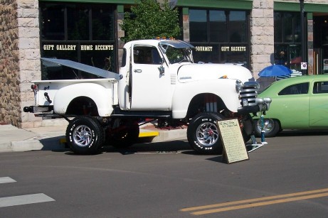 1972 Ford Ranchero - A white pickup truck is displayed on a street with a green car in the background.