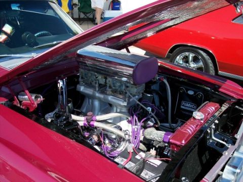 1972 Ford Ranchero - The engine bay of a red Ford Ranchero is open, revealing a powerful engine with custom purple detailing.