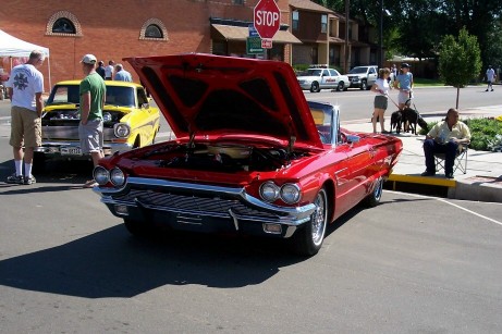 1972 Ford Ranchero - A red convertible is parked with its hood open, alongside other vehicles and people.