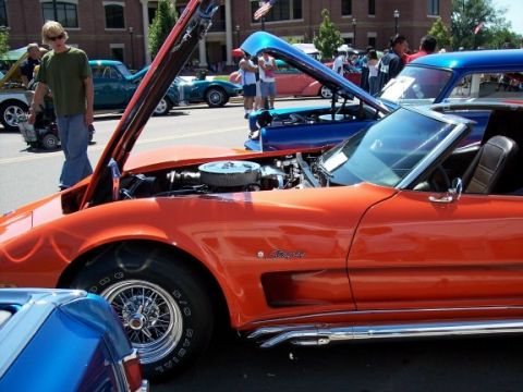 1972 Ford Ranchero - Orange 1975 Corvette Stingray on display with hood open, showing the engine. Other vehicles are visible in the background.