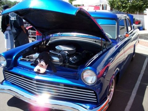 1972 Ford Ranchero - A custom blue sedan is displayed with its hood open, revealing the engine bay and a Goofy plush toy.
