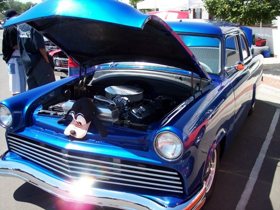 Blue custom sedan with hood open, showing engine and a Goofy hat on the front