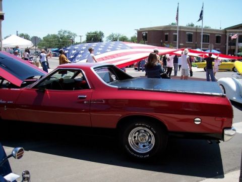 1972 Ford Ranchero - A red 1972 Ford Ranchero is displayed with a large American flag during an outdoor event.
