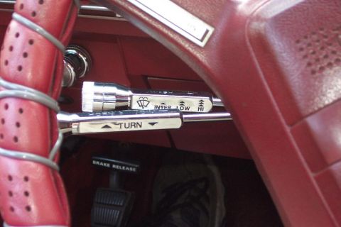 1985 Ford LTD Crown Victoria - Chrome turn-signal and wiper/washer control stalks on the red steering column of a classic vehicle, INTER LOW HI markings.