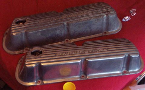 1985 Ford LTD Crown Victoria - Pair of finned cast-aluminum valve covers laid face-up on a red cloth, each embossed "POWERED BY FORD" with an oil-fill hole at the front c…