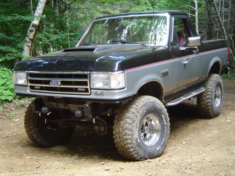 1989 Ford Bronco - This modified Ford Bronco sits high off the ground with large off-road tires, ready for adventure in the woods.