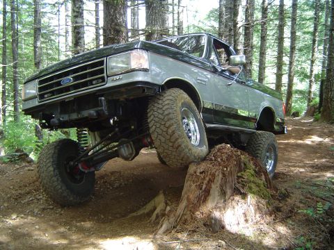 1989 Ford Bronco - This lifted 1987 Ford Bronco navigates a challenging off-road course, with one wheel on a large tree stump.