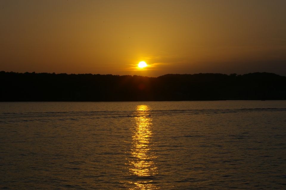 Sunset over water with a silhouetted tree line in the background. Text 'SUPERMOTORS' is visible