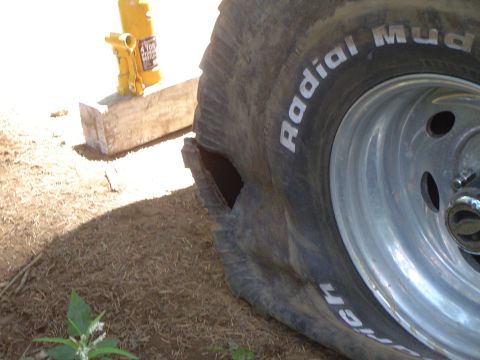1989 Ford Bronco - A damaged tire and a jack are visible, suggesting a tire change or repair is in progress.