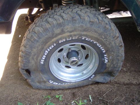 1989 Ford Bronco - A vehicle has a flat tire with a large gash on the sidewall.