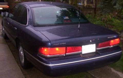 1995 Ford Crown Victoria - This Ford Crown Victoria has a dark blue paint job and chrome trim around the windows and bumper.