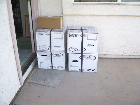 1991 Ford Bronco - Several boxes are stacked on a doormat near a doorway, with a textured wall in the background.