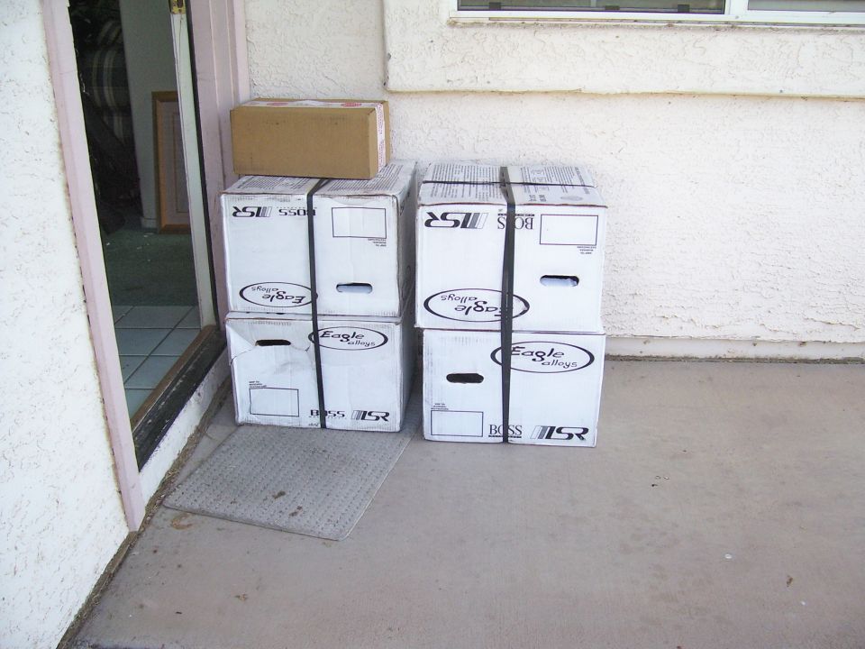Four Eagle Alloys wheel shipping boxes stacked on a stucco front porch