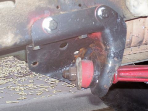 1991 Ford Bronco - Close-up view of a red suspension bushing attached to a black metal bracket, likely part of a vehicle's undercarriage.