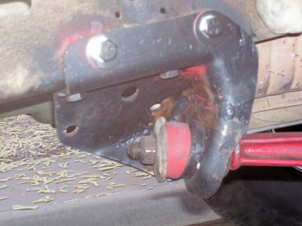 Radius arm frame bracket with red poly bushing under a truck chassis