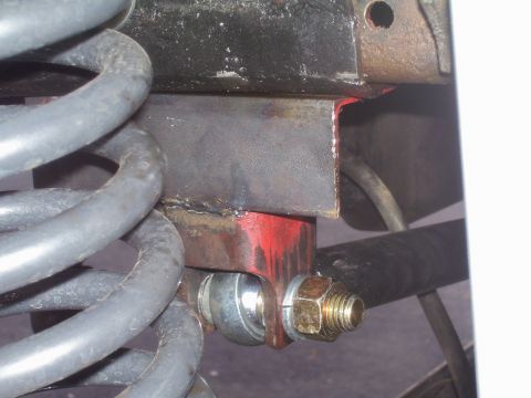 1991 Ford Bronco - This image shows a close-up of a vehicle's suspension system, focusing on a coil spring and a metal bracket.