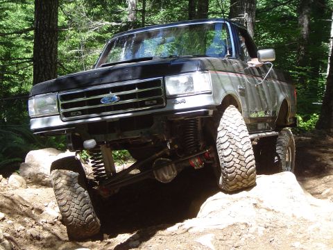 1989 Ford Bronco - This modified 1989 Ford Bronco navigates a challenging off-road course with its front tire high in the air.