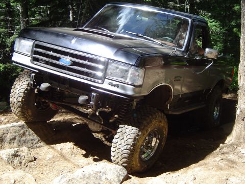 1989 Ford Bronco - This modified Ford F-Series truck navigates a challenging off-road path with large tires and lifted suspension.