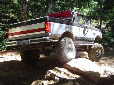 1989 Ford Bronco - This modified Ford Bronco is navigating a rocky trail in a wooded area.