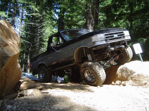 1989 Ford Bronco - Modified 1989 Ford Bronco tackles a rocky trail with its suspension clearly visible.