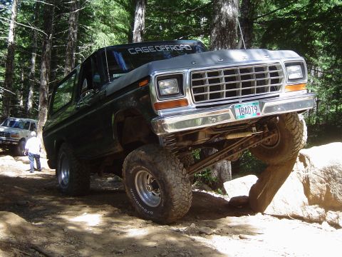 1989 Ford Bronco - A lifted 1978 Ford Bronco tackles an off-road obstacle with another vehicle visible in the background.
