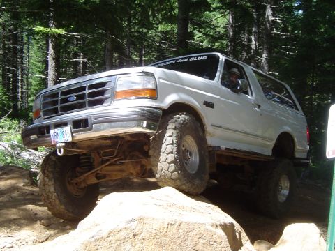 1989 Ford Bronco - This white Ford Bronco navigates a rocky off-road trail, its body style indicative of the early to mid-1990s.