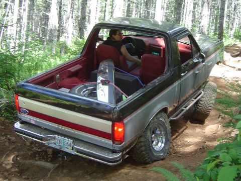 1989 Ford Bronco - This 1989 Ford Bronco is seen from the rear while navigating an off-road trail with a spare tire visible in the cargo area.