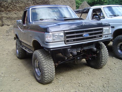 1989 Ford Bronco - This modified 1989 Ford Bronco features a lifted suspension and aggressive off-road tires, seen alongside another truck.