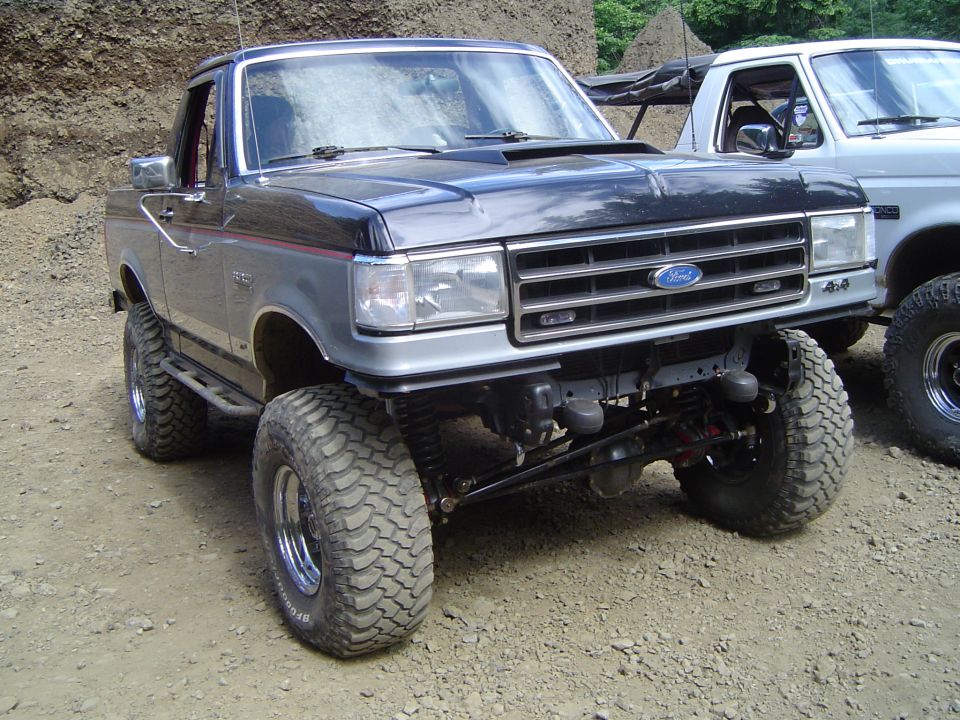 Lifted two-tone Ford Bronco on solid front axle and BFGoodrich mud tires at an off-road park
