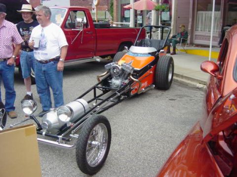 1995 Ford Probe - A dragster is parked on asphalt with a red truck and a red car nearby.