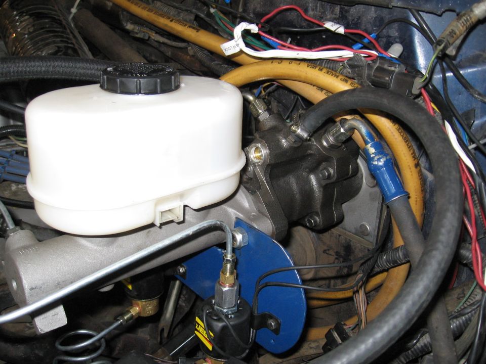 Brake master cylinder and booster assembly with yellow hoses and blue bracket