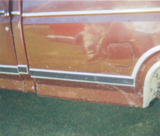 1984 Ford F-150 - This image shows the side of a red pickup truck, its trim and fuel door. The exact model and year are not identifiable from this view.