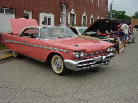 1995 Ford Probe - A vintage pink and white coupe with fins is displayed at a car show.