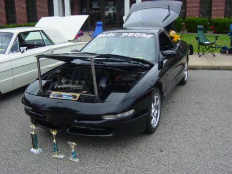 1995 Ford Probe - A black 1995 Ford Probe is displayed with its hood and trunk open, alongside trophies at a car show.
