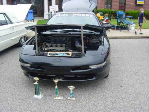 1995 Ford Probe - A black 1995 Ford Probe is displayed with its hood open, alongside several trophies at an outdoor event.