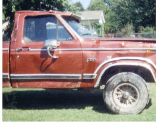 1984 Ford F-150 - This red pickup truck is shown from the side, with some visible damage to the body.