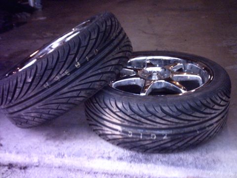 1995 Ford Probe - A pair of aftermarket chrome wheels with performance tires are displayed, with one wheel prominently featured.