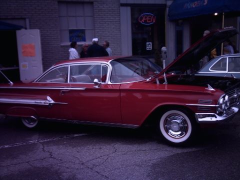 1995 Ford Probe - A red 1959 Chevrolet Impala is parked with its hood open, alongside another vehicle.