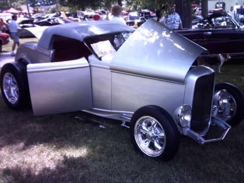 1995 Ford Probe - A silver hot rod is displayed with its hood and driver's door open, parked on grass at an outdoor event.