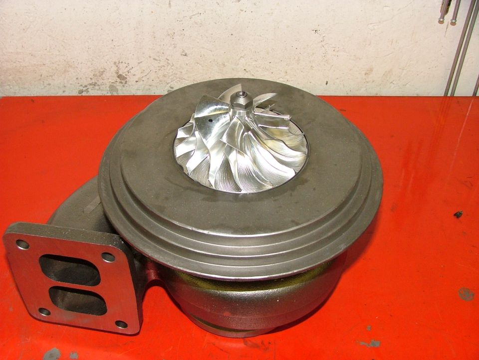 turbocharger with shiny fan blades on a red surface