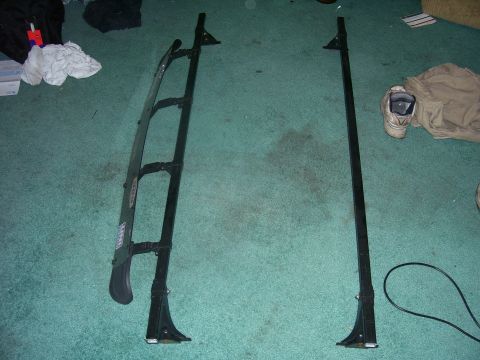 1991 Ford Bronco - Two parts of a ladder rack system are shown on a carpeted floor.