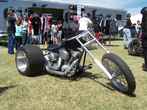 1995 Ford Probe - A custom chopper motorcycle is displayed outdoors, with a trailer selling merchandise in the background.