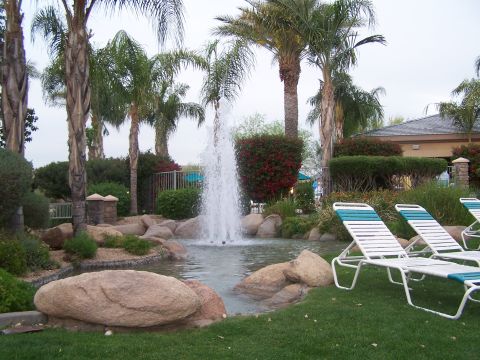 1995 Ford Probe - A tranquil resort scene features a splashing fountain surrounded by rocks and palm trees, with lounge chairs set on a manicured lawn.