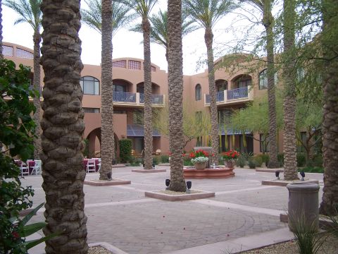 1995 Ford Probe - A courtyard scene with palm trees and a fountain in front of a multi-story building.