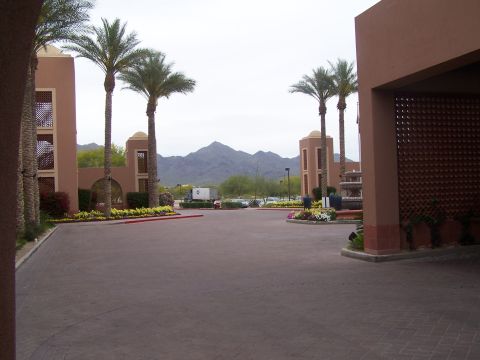 1995 Ford Probe - Entrance to a resort with palm trees and desert mountains under a cloudy sky.