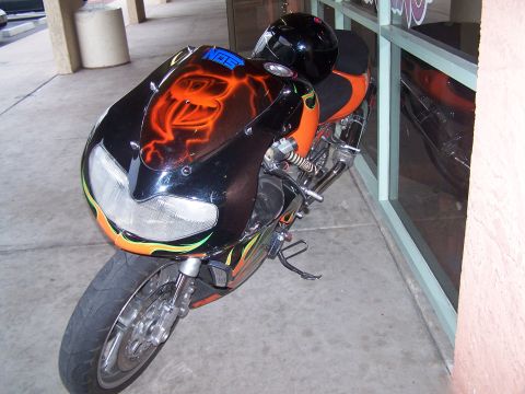 1995 Ford Probe - This motorcycle features custom flame and snake airbrushing on its front fairing, with a black helmet resting on the seat.