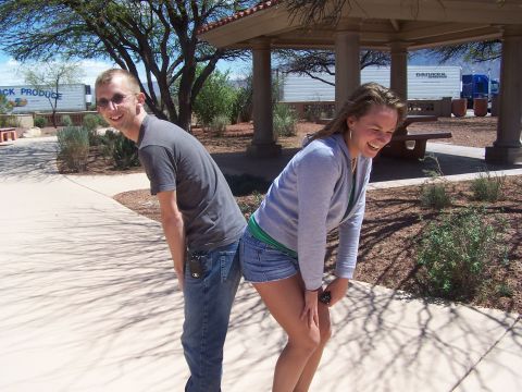 1995 Ford Probe - A man and woman pose humorously in front of parked trucks at a rest stop.