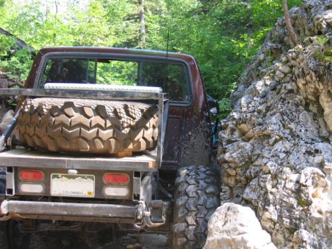 1981 Ford Bronco - This off-road vehicle is seen from the rear, with a spare tire mounted and navigating a tight spot between rocks.