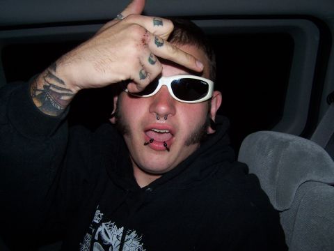 1995 Ford Probe - A man with numerous piercings and tattoos gestures with his hand while wearing sunglasses.