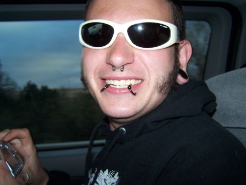 1995 Ford Probe - A man with extensive facial piercings and white sunglasses is captured in a close-up shot.